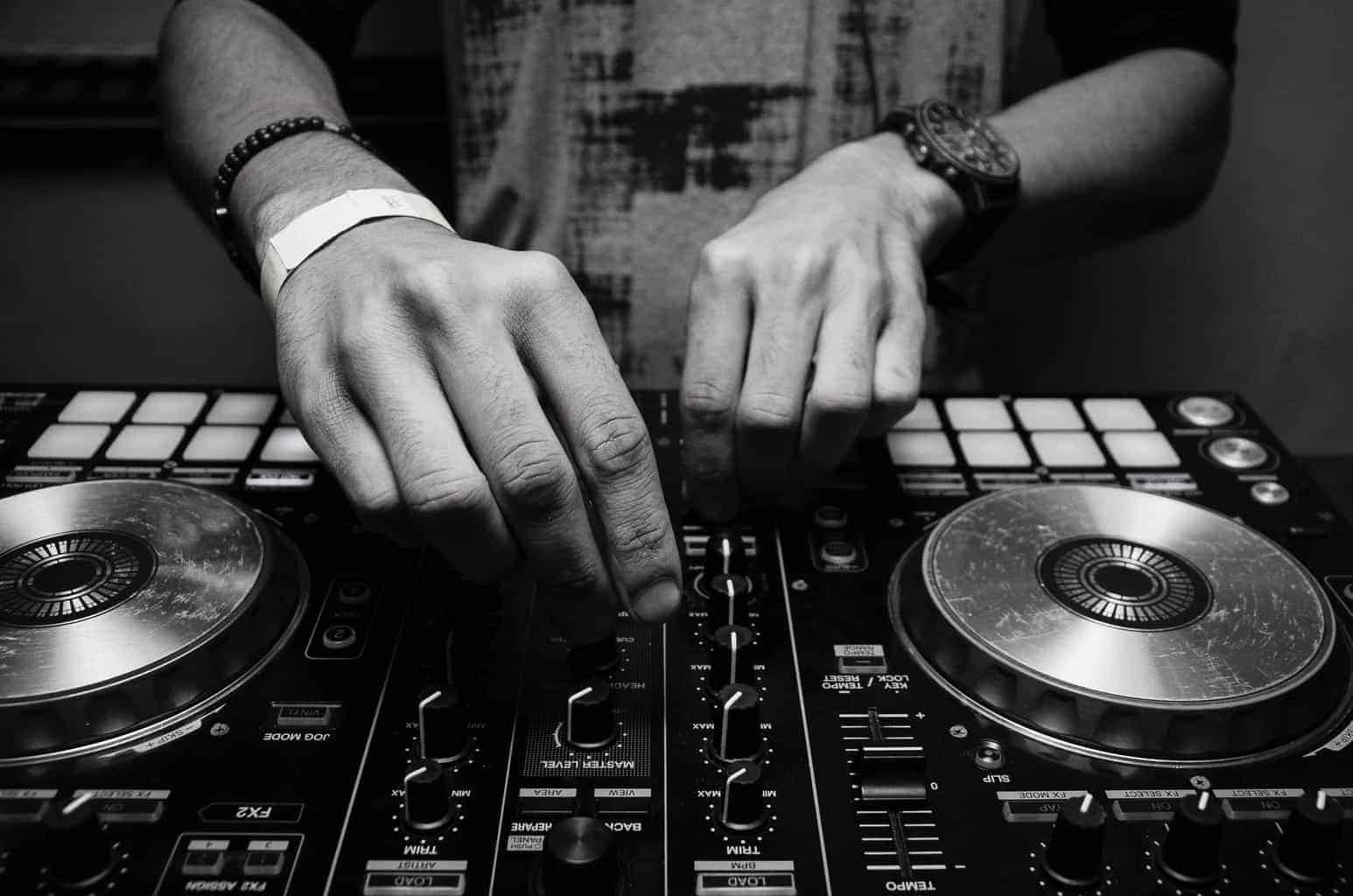 grayscale photography of person using dj controller